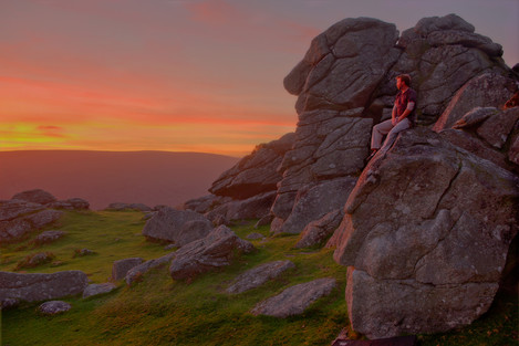 'Eventide' – climber Jon Hawker enjoying the afterglow light from the edge of a plutonic boulder at Bonehill, in Dartmoor National Park