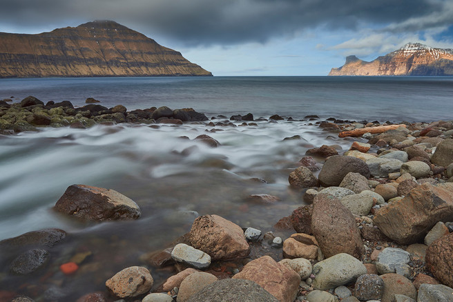 The brook Stórá splits the village of Elduvík in two parts. On the left mount Tyril (535 m). On the right the island of Kalsoy, illuminated by the sun.